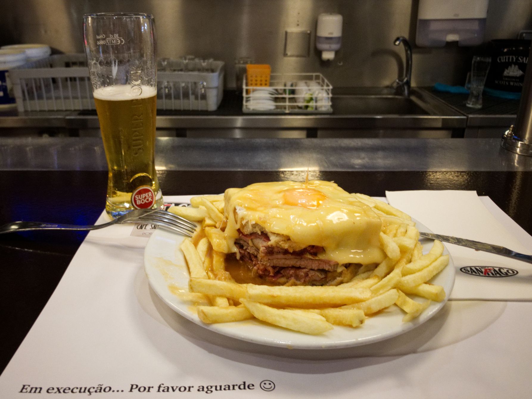 Three kinds of meat and sausage between toast slices and a fried egg gratinated with hearty cheese Café Santiago